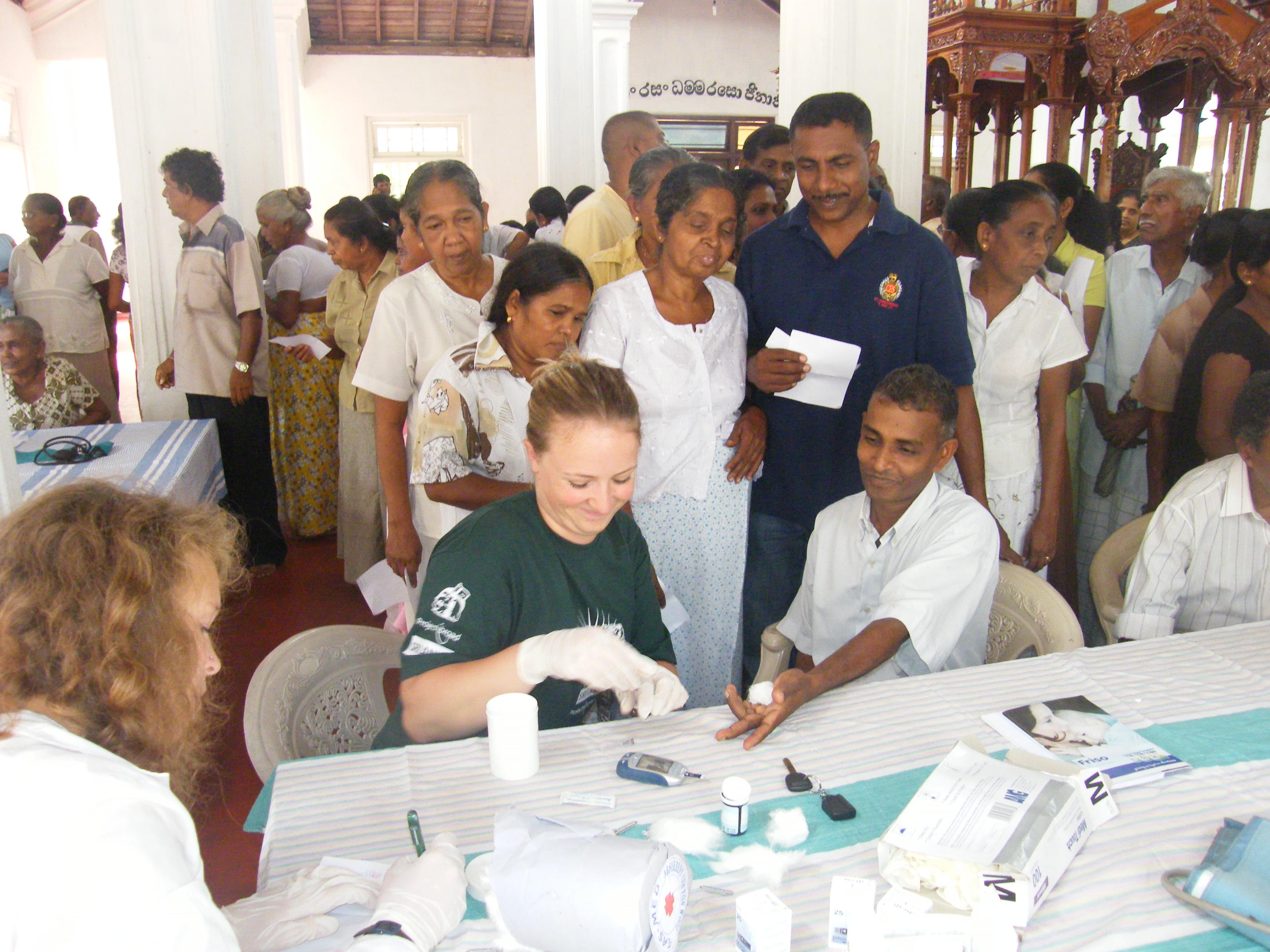 Two female interns from Projects Abroad helping patients at a medical camp whilst on their nursing internship in Sri Lanka. Two female interns on a nursing internship in Sri Lanka are seen helping at a medical camp assisting patients.